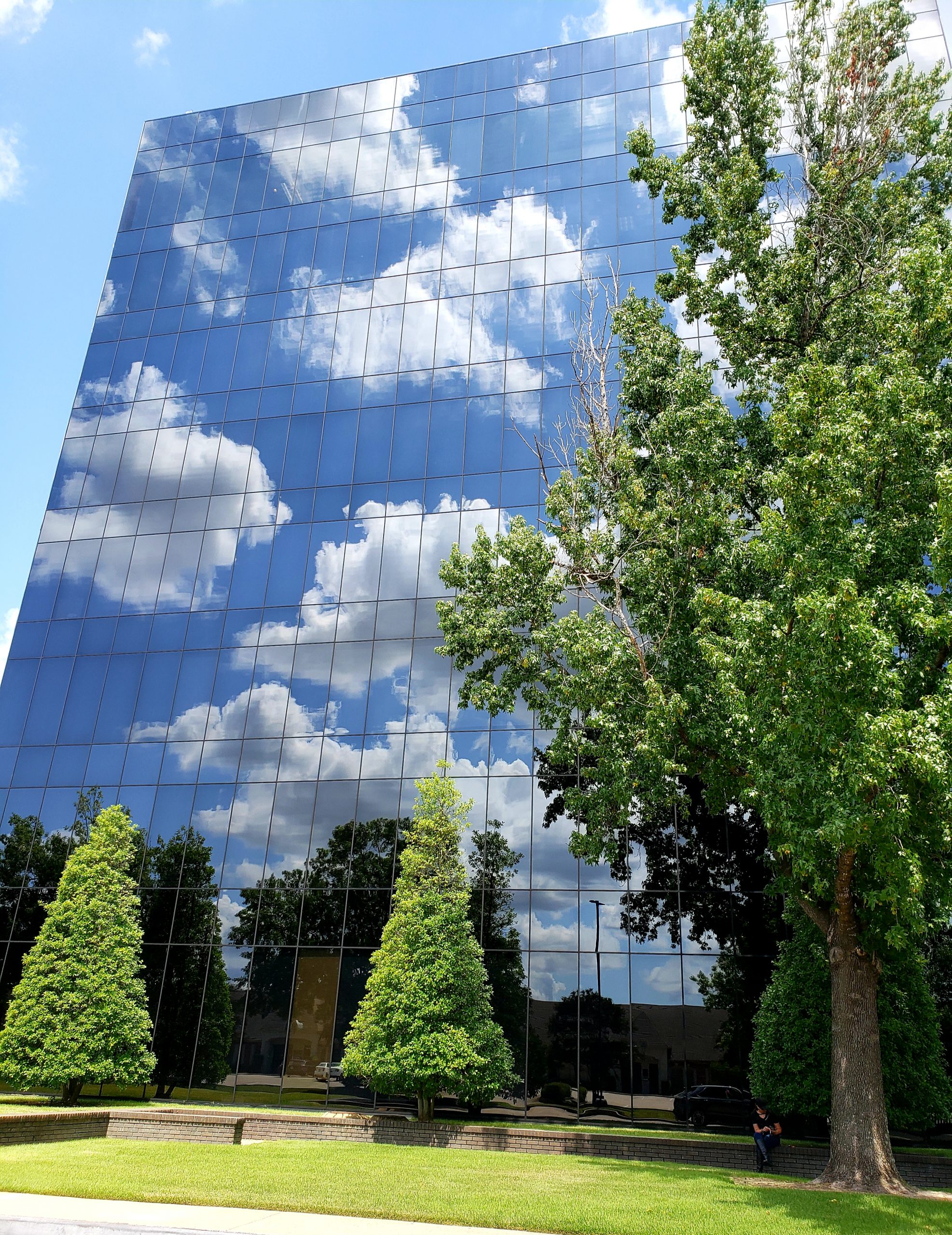 Exterior photo of clouds reflected in the windows on the side of Premier Plaza
